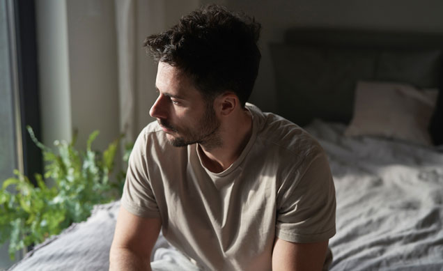 a man sitting on a bed depressed and struggling with dual diagnosis